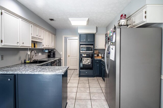 7265 E Wynfield Loop, Midland, GA 31820 - kitchen featuring stainless steel appliances, a peninsula, light tile patterned flooring, light countertops, and a textured ceiling