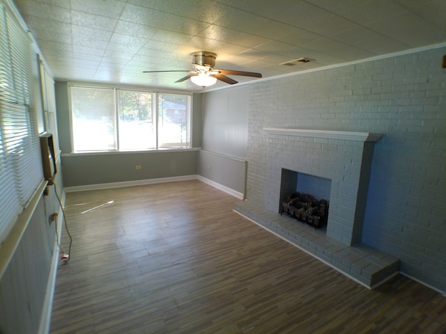 unfurnished living room featuring a fireplace, wood-type flooring, ceiling fan, and brick wall