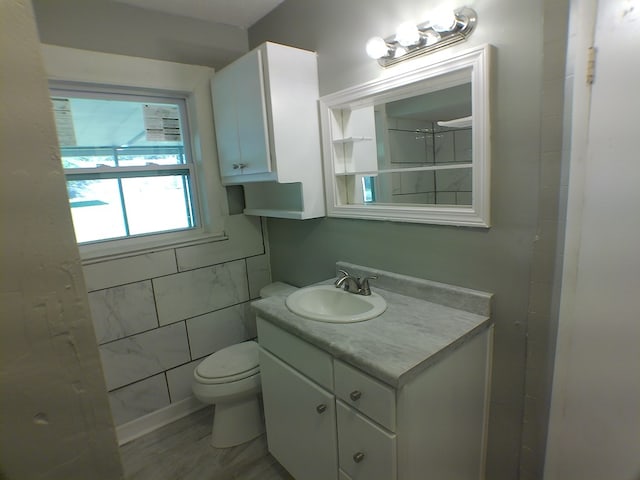 bathroom with vanity, toilet, and tile walls