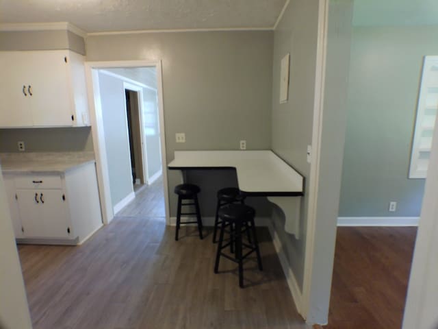 kitchen with white cabinets, dark wood-type flooring, a textured ceiling, and ornamental molding