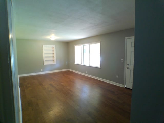 unfurnished room with dark wood-type flooring