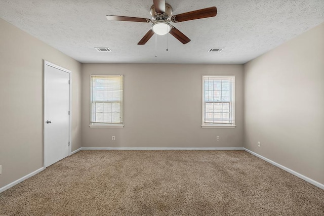 carpeted spare room featuring a wealth of natural light, visible vents, and a textured ceiling