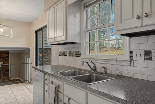 kitchen featuring a sink, backsplash, dark countertops, light tile patterned flooring, and dishwasher