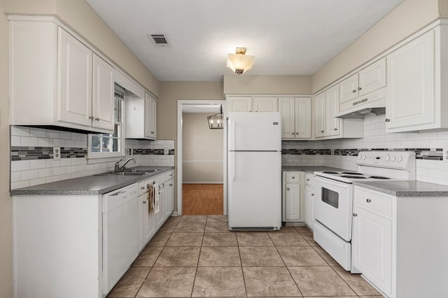 kitchen featuring white appliances, white cabinets, under cabinet range hood, and a sink