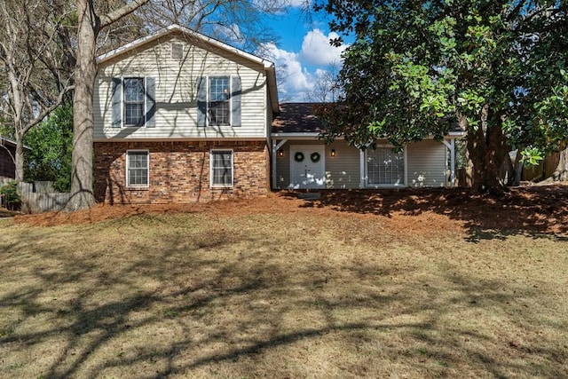 back of property with brick siding, a lawn, and fence