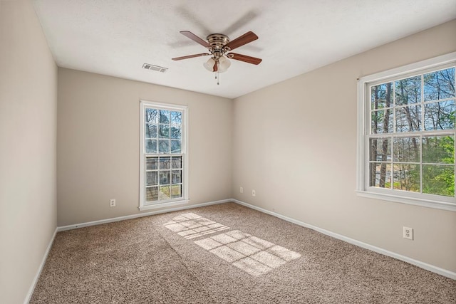 carpeted spare room with visible vents, baseboards, and a ceiling fan