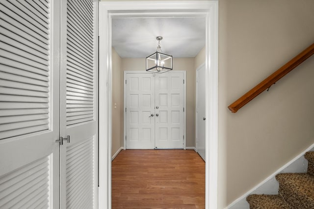 foyer entrance featuring baseboards, a notable chandelier, wood finished floors, and stairs