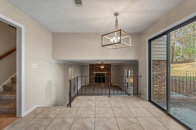 foyer with light tile patterned floors, visible vents, and a brick fireplace