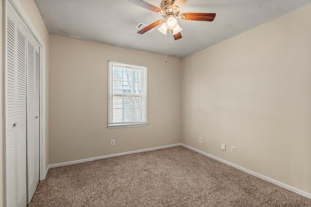 unfurnished bedroom featuring visible vents, a closet, carpet floors, baseboards, and ceiling fan