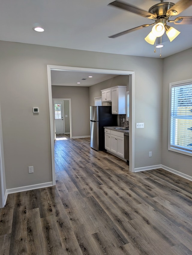 kitchen with stainless steel appliances, white cabinets, ceiling fan, decorative backsplash, and dark wood-type flooring