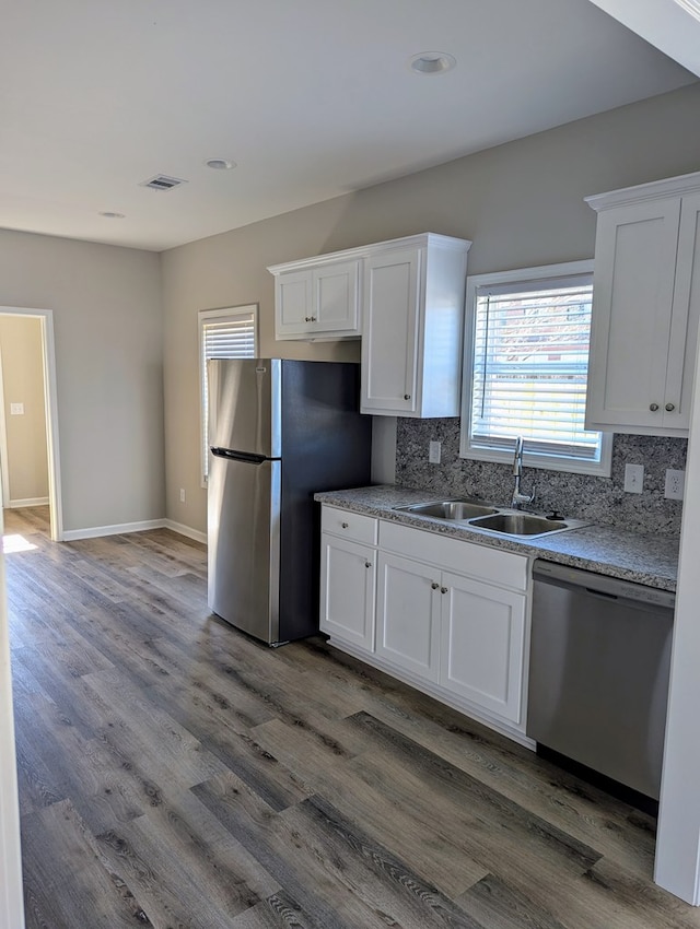 kitchen featuring stainless steel appliances, white cabinets, decorative backsplash, and sink