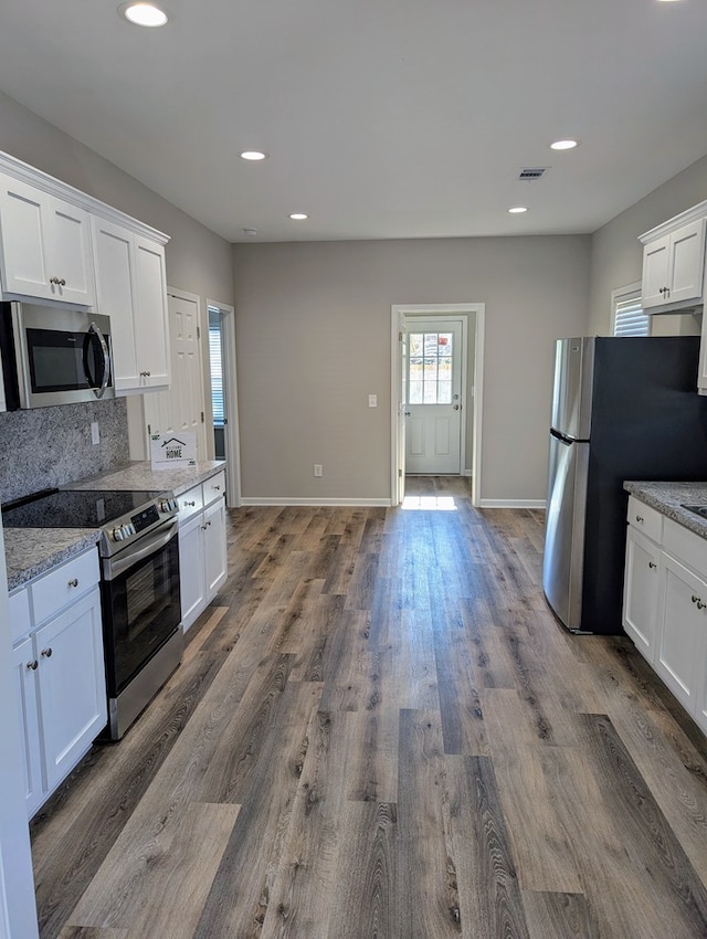 kitchen featuring appliances with stainless steel finishes, white cabinetry, and light stone countertops