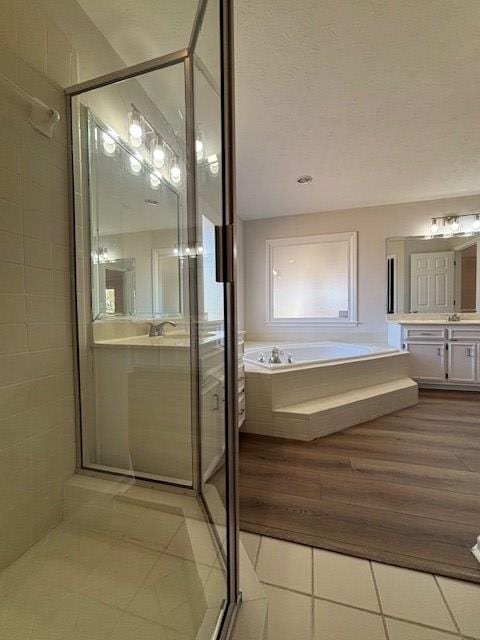 full bathroom with a stall shower, tile patterned flooring, a garden tub, and vanity