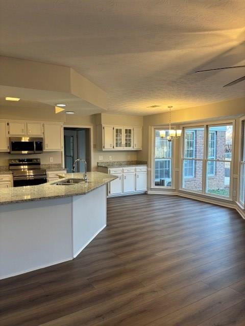 kitchen with white cabinets, dark wood-style flooring, stainless steel appliances, and a sink