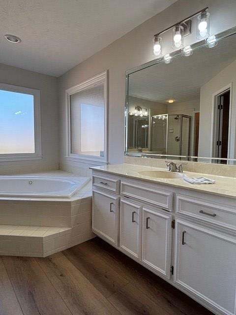 bathroom with a bath, a shower stall, wood finished floors, and vanity