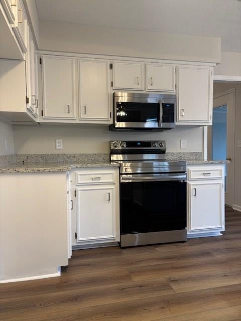 kitchen with white cabinets, light stone counters, stainless steel appliances, and dark wood-type flooring