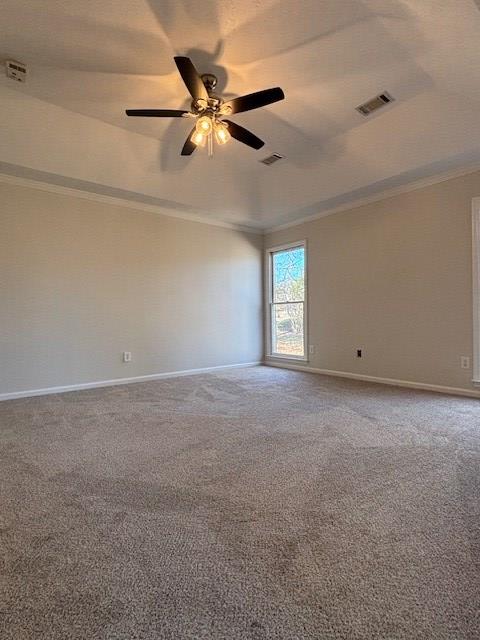 carpeted empty room featuring a ceiling fan, visible vents, crown molding, and baseboards