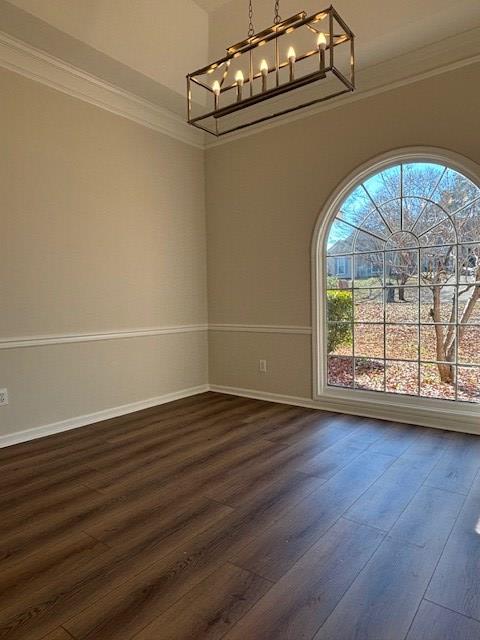 unfurnished dining area featuring a notable chandelier, ornamental molding, dark wood finished floors, and baseboards