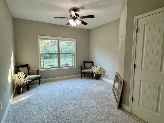 living area featuring a textured ceiling, ceiling fan, and light carpet