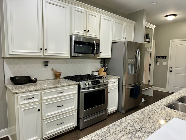 kitchen with white cabinetry, light stone countertops, dark wood-type flooring, and appliances with stainless steel finishes