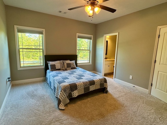 carpeted bedroom with connected bathroom, multiple windows, and ceiling fan