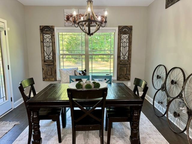 dining area featuring dark wood-type flooring and an inviting chandelier