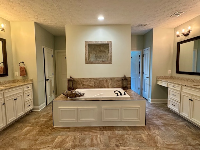 bathroom featuring vanity, a bathtub, and a textured ceiling