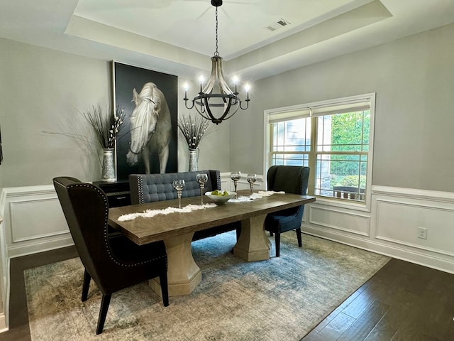 dining room with a raised ceiling, an inviting chandelier, and hardwood / wood-style flooring