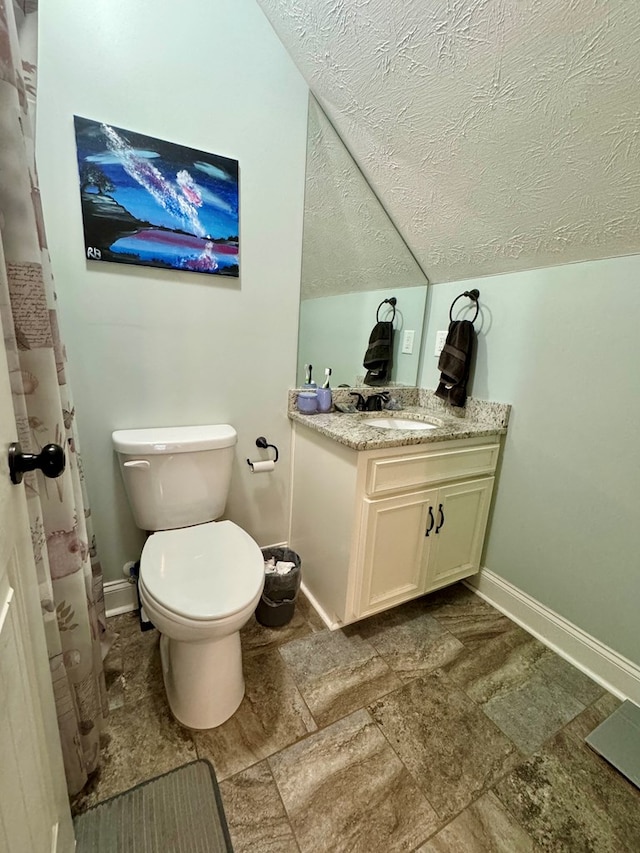 bathroom with toilet, a textured ceiling, vanity, and vaulted ceiling