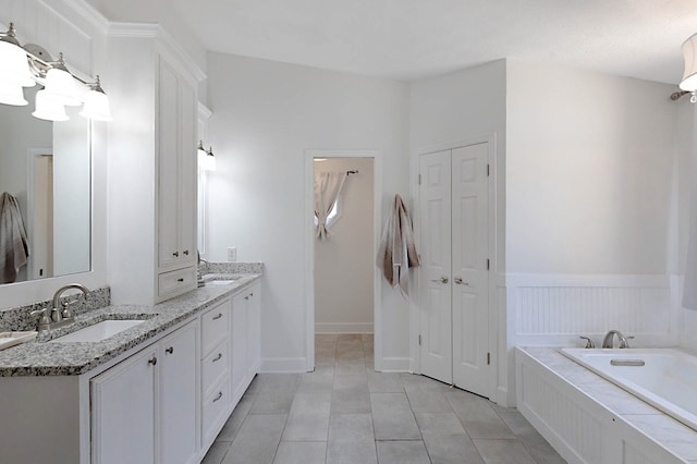 7191 Otter Dr, Midland, GA 31820 - full bathroom featuring double vanity, a closet, a bath, tile patterned floors, and a wainscoted wall