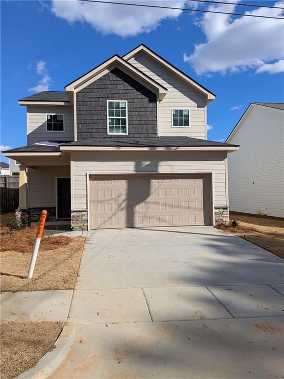 craftsman house featuring driveway, stone siding, an attached garage, and fence