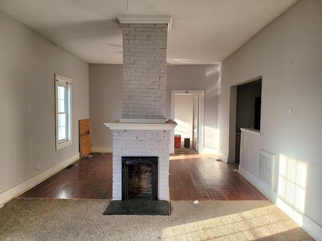 unfurnished living room with hardwood / wood-style flooring, a fireplace, visible vents, and baseboards