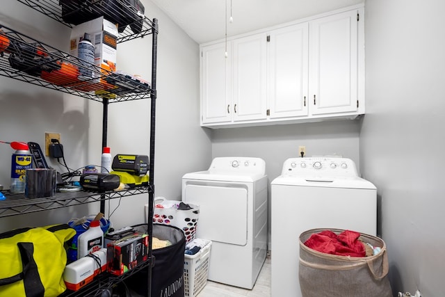 clothes washing area with cabinets and washing machine and clothes dryer