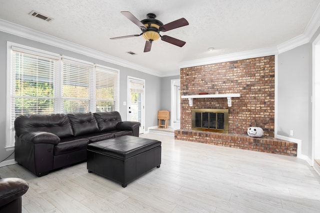 living room with crown molding, a fireplace, a textured ceiling, and light wood-type flooring