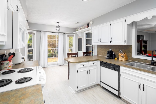 kitchen featuring sink, white cabinets, decorative backsplash, white dishwasher, and kitchen peninsula