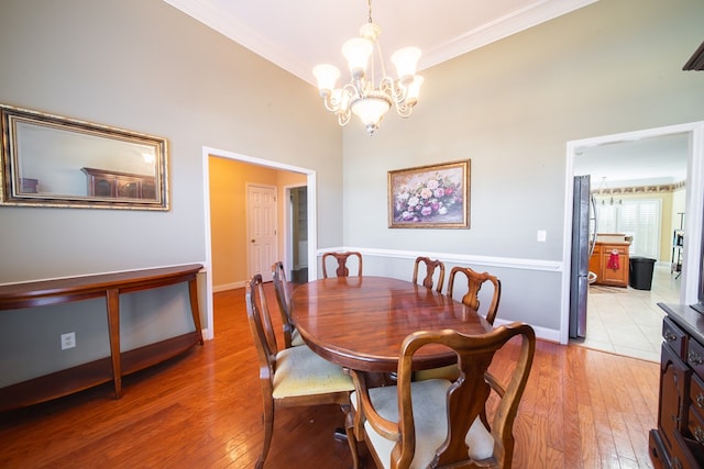 dining area featuring crown molding, lofted ceiling, a chandelier, and light hardwood / wood-style floors