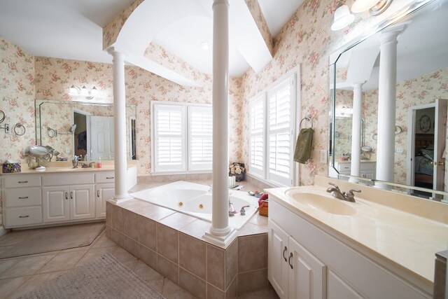 bathroom with a relaxing tiled tub, tile patterned floors, vanity, and ornate columns