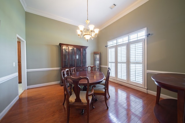 dining room featuring wood-type flooring, crown molding, and an inviting chandelier