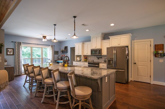 299 Savior Ln, Hamilton, GA 31811 - kitchen with appliances with stainless steel finishes, a breakfast bar area, light stone counters, backsplash, and white cabinets