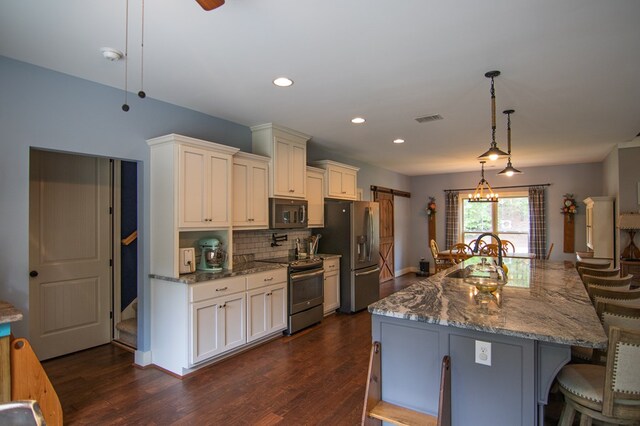299 Savior Ln, Hamilton, GA 31811 - kitchen with appliances with stainless steel finishes, a kitchen bar, backsplash, dark wood-type flooring, and hanging light fixtures