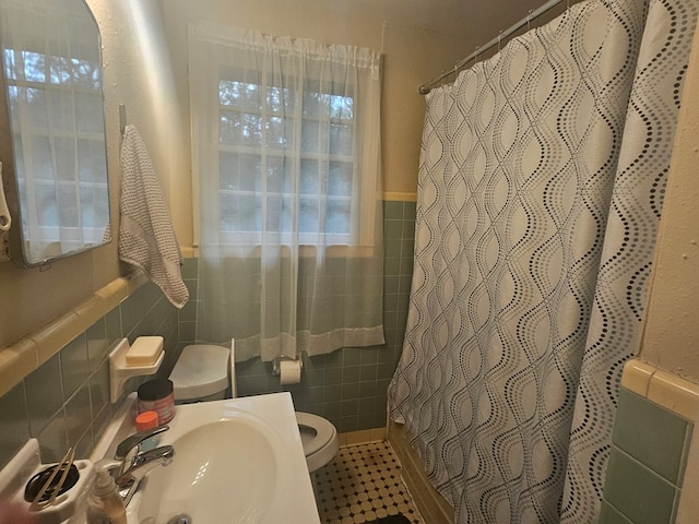 bathroom with sink, a shower with shower curtain, tile walls, and toilet