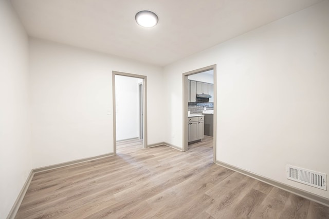unfurnished room featuring baseboards, visible vents, and light wood-style flooring