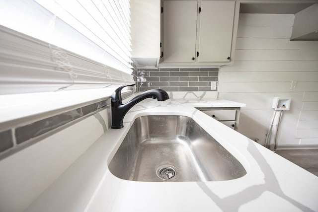interior details with light stone countertops, decorative backsplash, and a sink