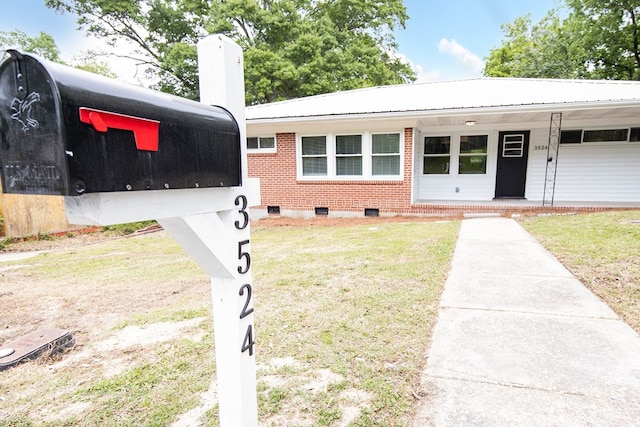 view of front of property featuring crawl space, a front lawn, covered porch, metal roof, and brick siding