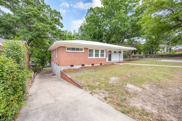 ranch-style home with a front lawn, concrete driveway, covered porch, brick siding, and metal roof