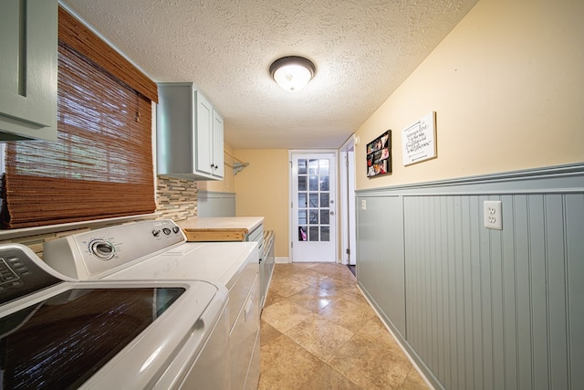 washroom with wainscoting, cabinet space, a textured ceiling, and independent washer and dryer