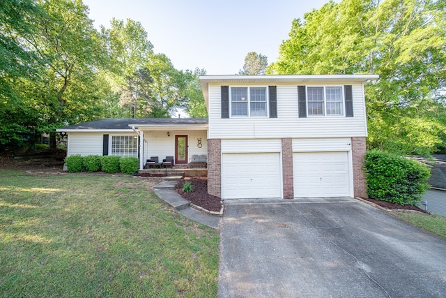 tri-level home featuring a garage, brick siding, aphalt driveway, and a front yard