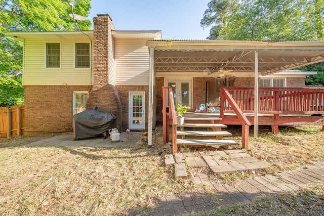 back of house with fence, a wooden deck, a chimney, and brick siding
