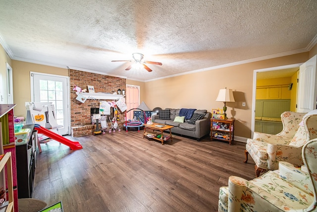 living room featuring a textured ceiling, ornamental molding, a brick fireplace, wood finished floors, and a ceiling fan