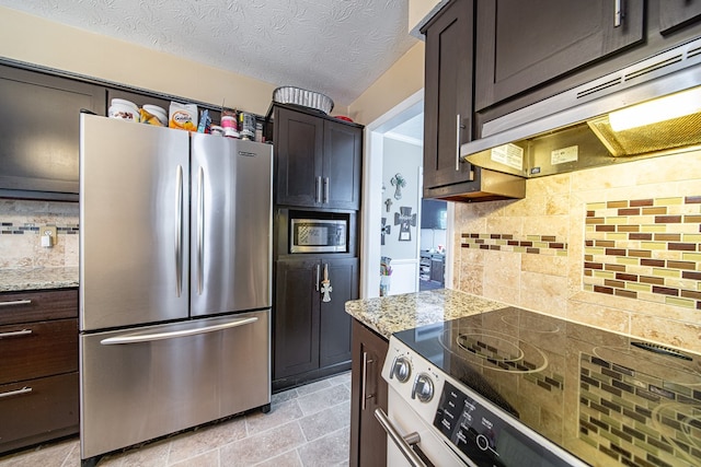kitchen featuring light stone counters, tasteful backsplash, stainless steel appliances, and under cabinet range hood